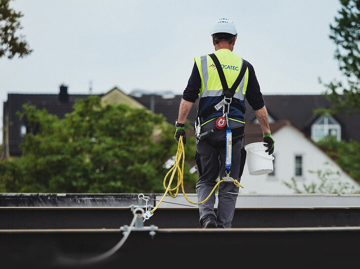 LOCATEC Mitarbeiter sichert sich auf einem Flachdach zur Leckortung von Undichtigkeiten.